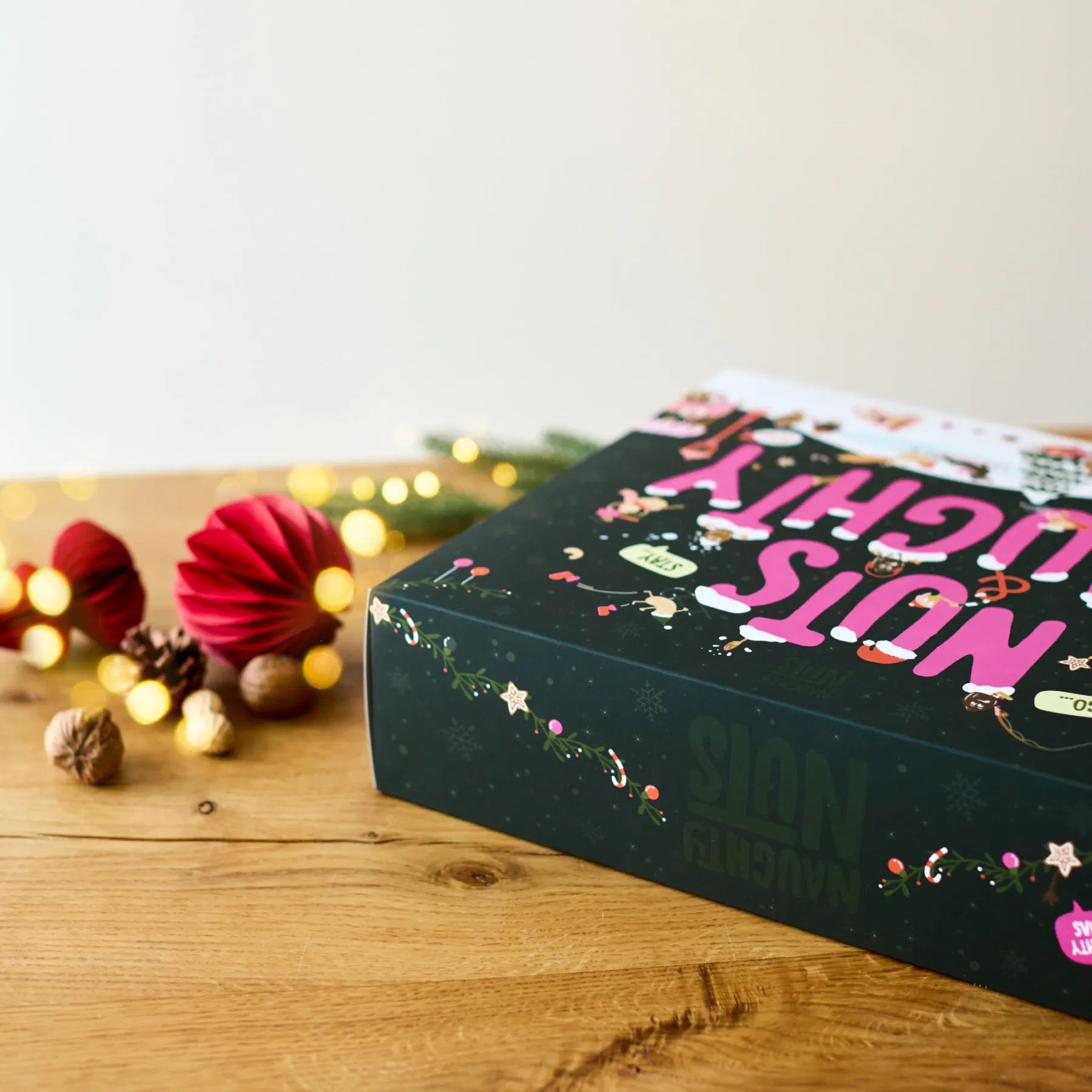 Adventskalender Deluxe 2026 auf einem Holztisch mit weihnachtlicher Dekoration